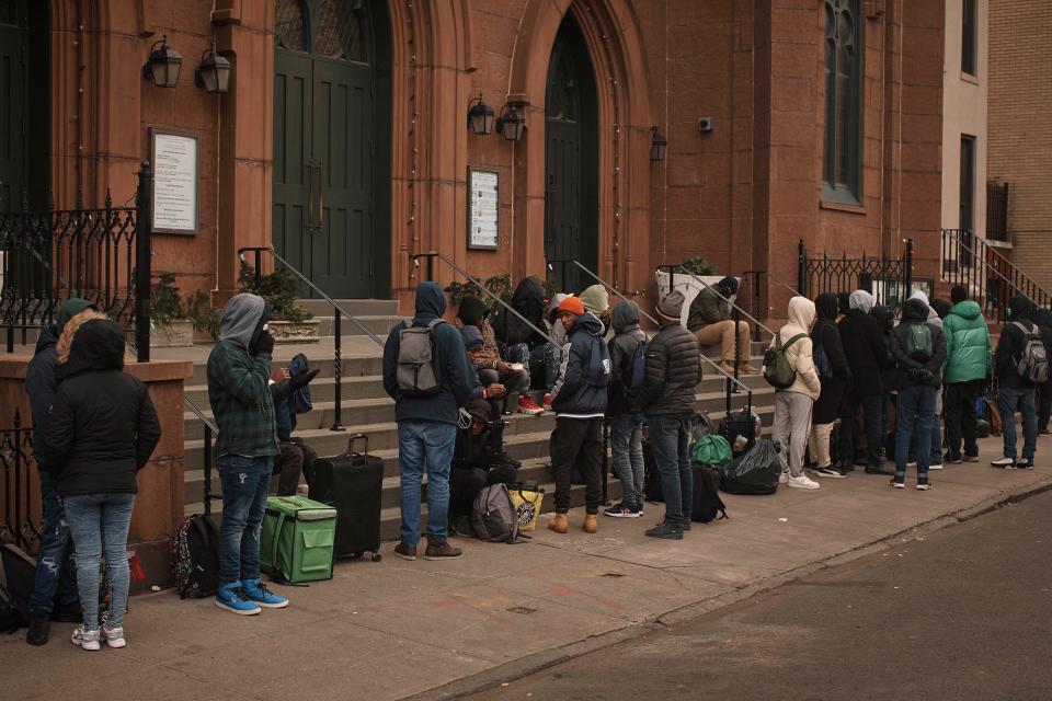 Migrants queue in the cold as they look for a shelter outside a Migrant Assistance Center at St. Brigid Elementary School on Tuesday, Dec. 5, 2023, in New York.