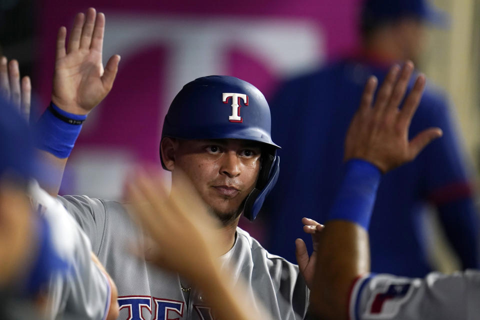 Texas Rangers' Yohel Pozo is high-fived in the dugout after scoring on a double by Jose Trevino during the seventh inning of a baseball game against the Los Angeles Angels Monday, Sept. 6, 2021, in Anaheim, Calif. (AP Photo/Marcio Jose Sanchez)