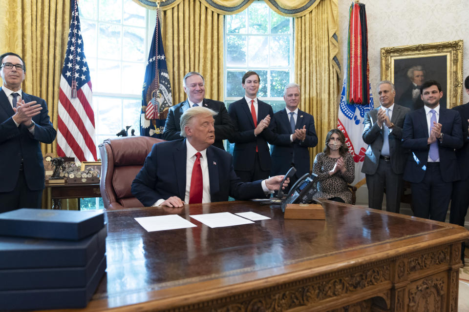 President Donald Trump hangs up a phone call with the leaders of Sudan and Israel, as Treasury Secretary Steven Mnuchin, left, Secretary of State Mike Pompeo, White House senior adviser Jared Kushner, National Security Adviser Robert O'Brien, and others applaud in the Oval Office of the White House, Friday, Oct. 23, 2020, in Washington. (AP Photo/Alex Brandon)