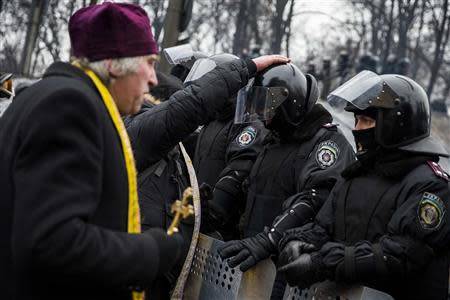 Clerics bless riot police officers standing in formation facing anti-government protesters in Kiev, January 28, 2014. REUTERS/Thomas Peter