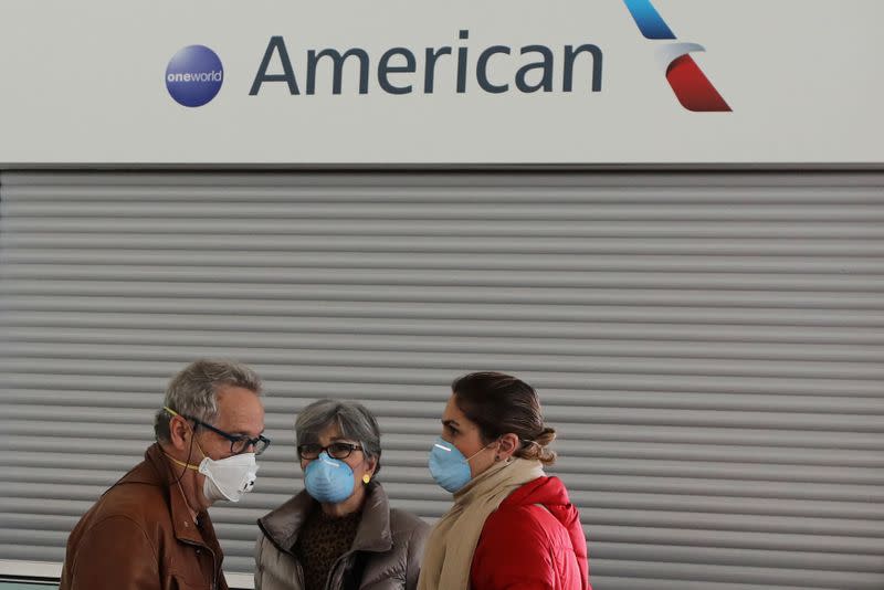 Passengers wear protective face masks as they stand in front of the American Airlines ticketing desk at Josep Tarradellas Barcelona-El Prat Airport, after further cases of coronavirus were confirmed in Barcelona