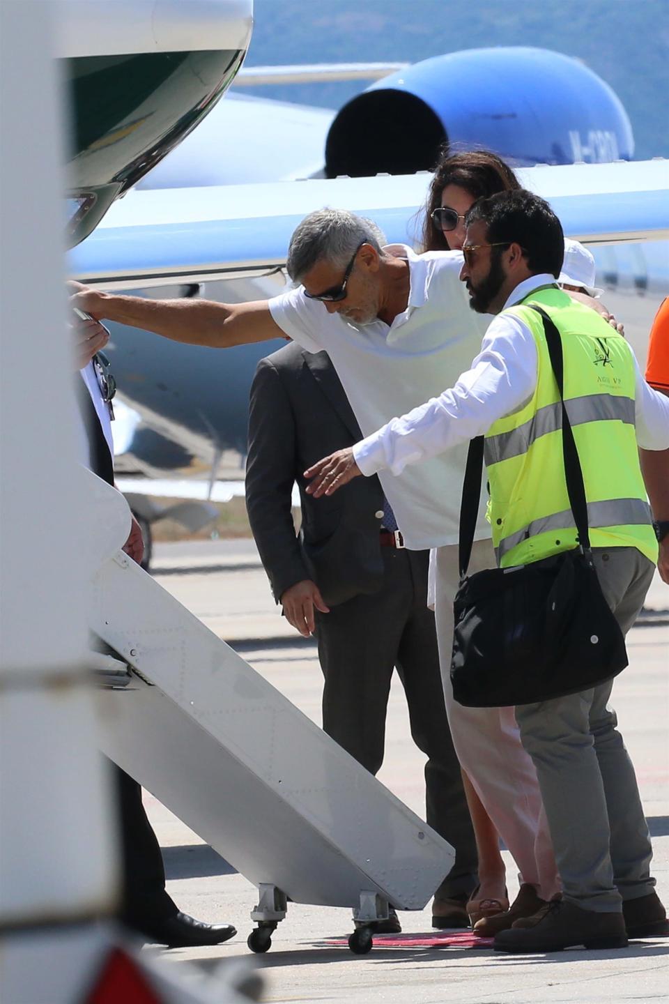 George Clooney and his wife, Amal, prepare to leave Sardinia on July 12 after the actor was released from the hospital following a motorbike accident. Source: BackGrid