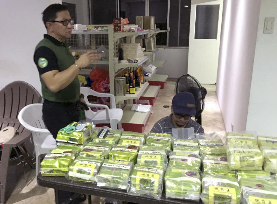 In this Tuesday, March 19, 2019, photo provided by Philippine Drug Enforcement Agency, PDEA, Aaron Aquino, PDEA Chief, stands next to more than 160 kilos (353 pounds) of methamphetamine concealed in tea wrappers following "buy-bust" raids in Alabang township, Muntinlupa city east of Manila, Philippines. It was PDEA's second largest drug haul this year in a sign of how the problem has persisted despite the president's bloody crackdown on illegal drugs. Aquino said Wednesday, March 20, 2019, three Chinese nationals and a Chinese-Filipino man, who works as an interpreter, were arrested, with the drugs concealed in tea wrappers similar to those seized in Malaysia, Thailand and Myanmar and indicated an international drug syndicate was behind the trafficking. (Sheila Valmoria, Philippine Drug Enforcement Agency PIO via AP)