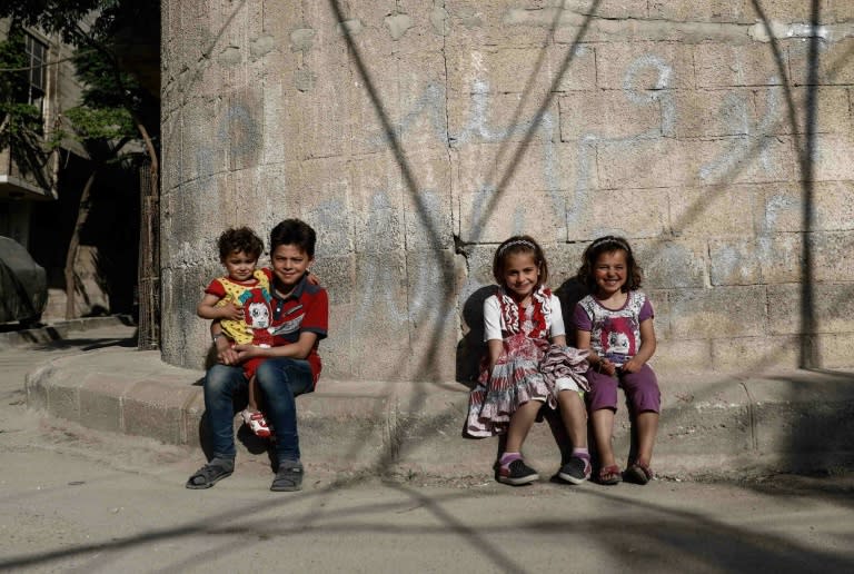 Syrian children pose for a photo near their house in the rebel-held town of Douma on the eastern outskirts of Damascus on May 6, 2017