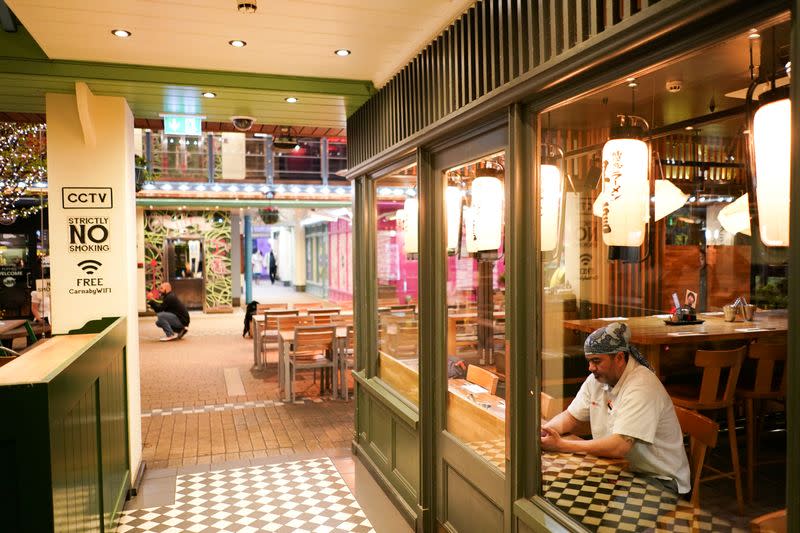 FILE PHOTO: A restaurant worker sits in the window of an empty restuarant, as the number of coronavirus (COVID-19) cases grow around the world, in London