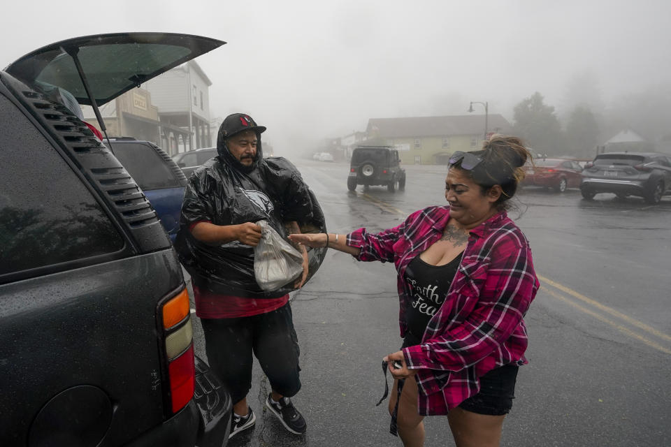 Ruben Ornelas, left, unpacks plastic raincoats for the family with his wife, Stephanie, as wind and rain pummel the area Friday, Sept. 9, 2022, in Julian, Calif. A tropical storm nearing Southern California has brought fierce mountain winds, high humidity, rain and the threat of flooding to a region already dealing with wildfires and an extraordinary heat wave. (AP Photo/Gregory Bull)