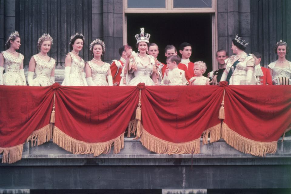 2nd June 1953:  The newly crowned Queen Elizabeth II waves to the crowd from the balcony at Buckingham Palace. Her children Prince Charles and Princess Anne stand with her.  (Photo by Hulton Archive/Getty Images)