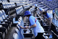 Workers clean seats between softball games at the 2020 Summer Olympics, Saturday, July 24, 2021, in Yokohama, Japan. (AP Photo/Matt Slocum)