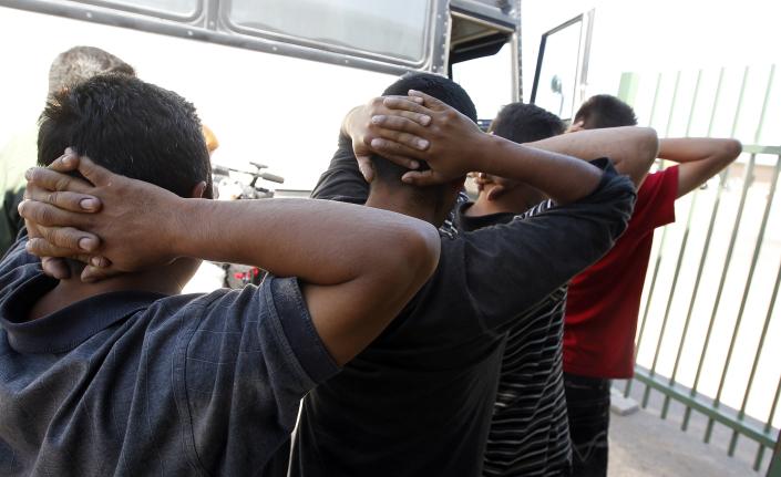 In this Aug. 9, 2012 file photo, newly arrived people who were caught in Arizona by the U.S. Border Patrol, are initially processed at Tucson Sector U.S. Border Patrol Headquarters in Tucson, Ariz. A major U.S. effort to discourage repeated attempts by immigrants to enter the country illegally by flying and busing them into Mexico hundreds of miles away from where they were caught has been sharply scaled back after producing relatively modest gains. (AP Photo/Ross D. Franklin, file)