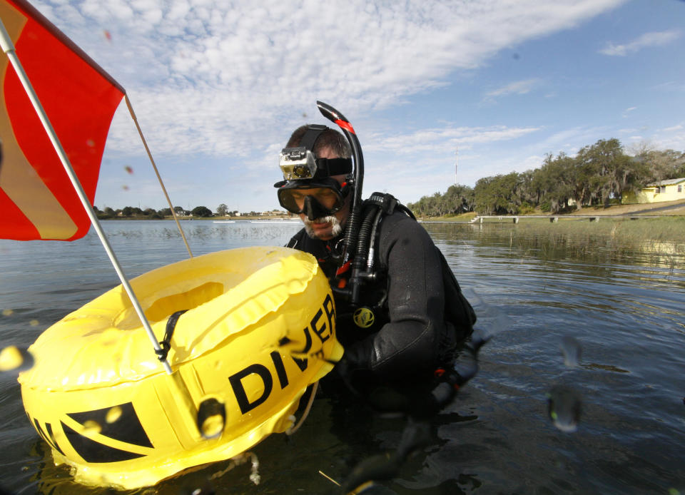 In this Saturday, Jan. 14, 2012 photo, Kenny Jenkins hooks a line to a float with a "Diver Down" flag as he prepares to place a geocache in about 33 ft. of water in Lake Denton in Avon Park Fla. Interest in geocaching has grown significantly over the years. But combining the two hobbies, geocaching and scuba diving, has only recently taken off. About 100 geocaches around the world today are only accessible with scuba gear, according to the geocaching.com database. (AP Photo/Wilfredo Lee)