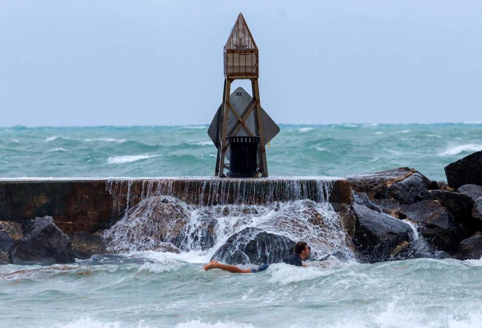 A surfer takes advantage of the weather by the Bal Harbour Lighthouse as the waves crash against the jetty on April 12, 2023, in Bal Harbour, Florida.