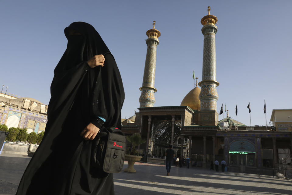 In this Saturday, June 13, 2020, photo, a Muslim pilgrim walks in the courtyard at the shrine of the Saint Abdulazim in Shar-e-Ray, south of Tehran, Iran. Going inside is prohibited due the coronavirus. (AP Photo/Vahid Salemi)