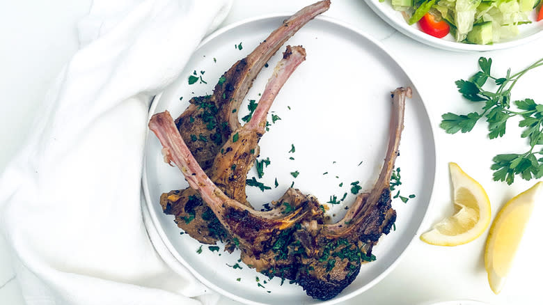 lamb chops on plate with lemon and parsley garnish