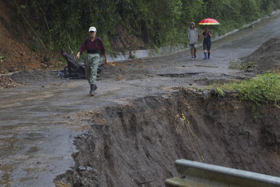 <p>Neighbors walk under the rain past a washed out road in Alajuelita on the outskirts of San Jose, Costa Rica, Thursday, Oct. 5, 2017. (Photo: Moises Castillo/AP) </p>