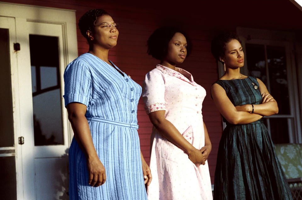 three women in dresses standing on a porch