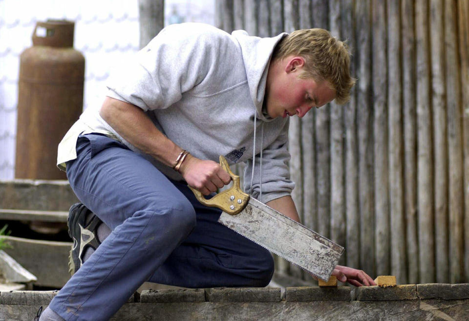 FILE - Britain's Prince William carries out maintainance work in the village of Tortel, Southern Chile during his Raleigh International expedition in this recent but undated photo made available Monday Dec. 11, 2000. The world watched as Prince William grew from a towheaded schoolboy to a dashing air-sea rescue pilot to a father of three. But as he turns 40 on Tuesday, June 21, 2022, William is making the biggest change yet: assuming an increasingly central role in the royal family as he prepares for his eventual accession to the throne. (Toby Melville/Pool Photo via AP, FIle)