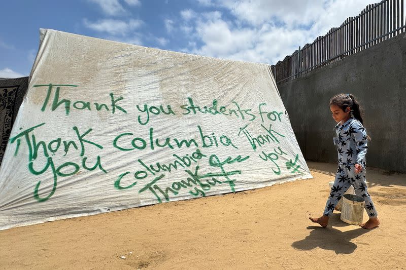 FILE PHOTO: A girl walks next to a tent, in Rafah