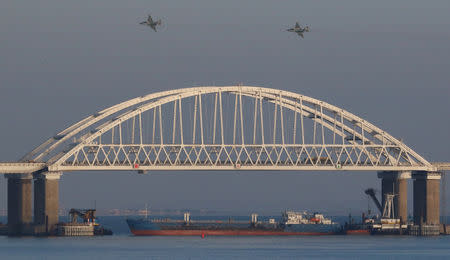 Russian jet fighters fly over a bridge connecting the Russian mainland with the Crimean Peninsula with a cargo ship beneath it after three Ukrainian navy vessels were stopped by Russia from entering the Sea of Azov via the Kerch Strait in the Black Sea, Crimea November 25, 2018. REUTERS/Pavel Rebrov