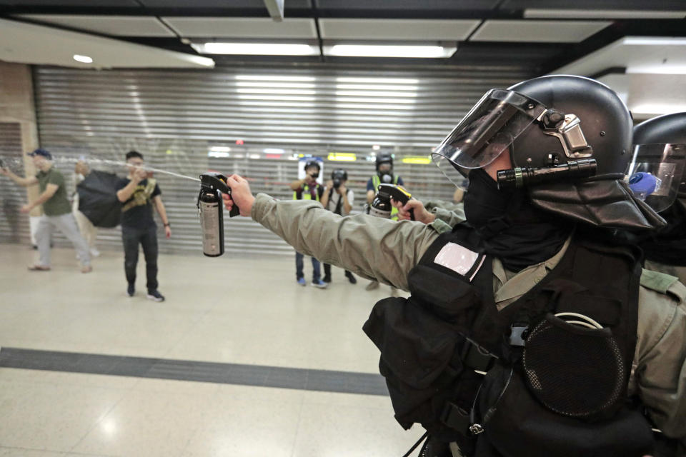 A riot police officer fires pepper spray toward people at a shopping mall in Hong Kong, Sunday, Nov. 3, 2019. Riot police stormed several malls in Hong Kong on Sunday in a move to thwart more pro-democracy protests, as the city's leader heads to Beijing for talks on deepening economic integration between the semi-autonomous Chinese territory and mainland China. (AP Photo/Dita Alangkara)