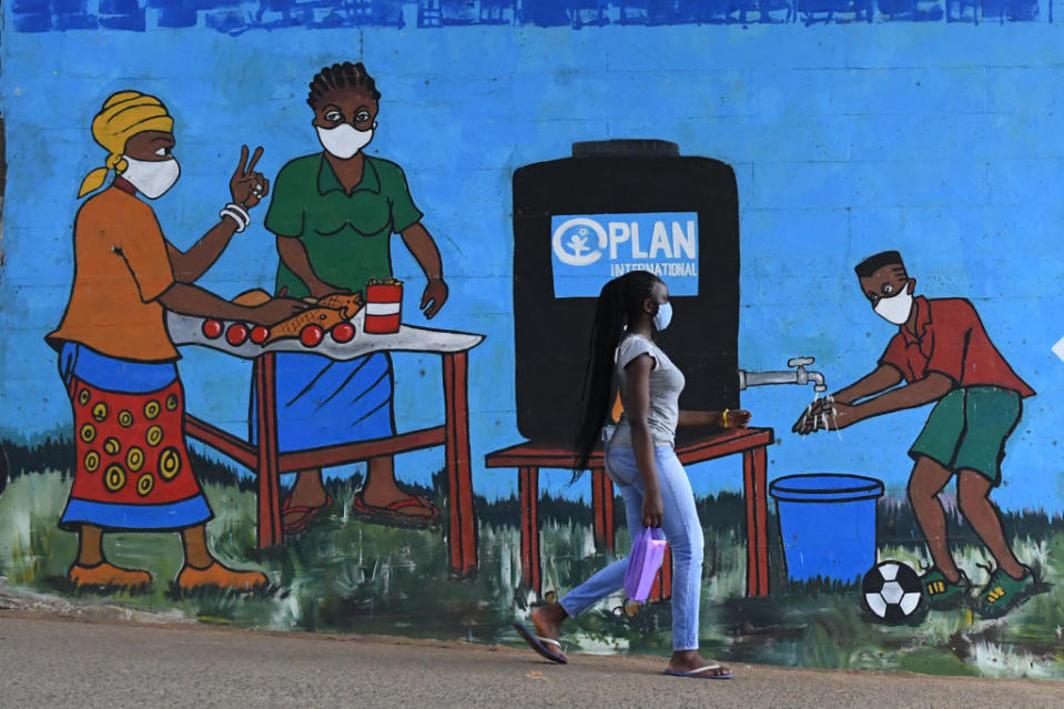 A woman walks past graffiti that promotes hand washing and wearing face masks in Nairobi.