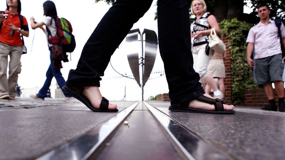 Ein Tourist geht über den Nullmeridian in Greenwich, London.  - Fernsehnachrichten/Shutterstock