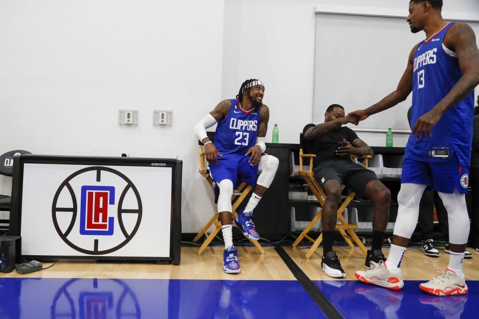 Robert Covington and John Wall greet Paul George during media day for the Clippers.