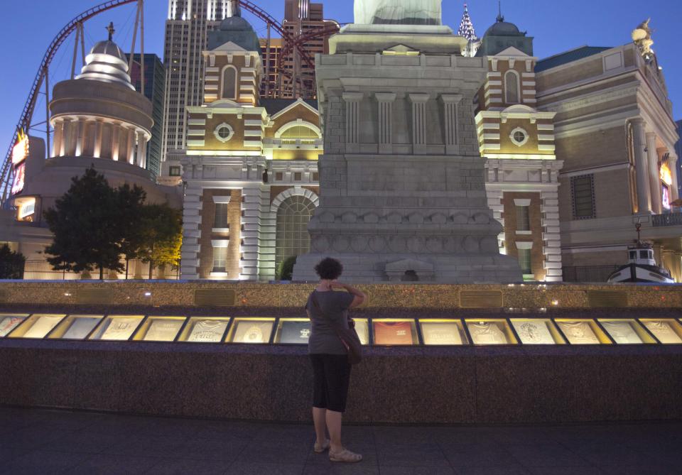 FILE-In this June 22, 2011 file photo, a woman stops to look at the September 11 memorial outside the New York, New York casino, in Las Vegas. The memorial, which held a rotating collection of firefighter t-shirts commemorating the lives lost in the attacks on the World Trade Center, has been demolished and will be relocated by MGM Resorts International to make way for a $100 million renovation of the promenade in front of 16 year-old Manhattan-themed casino and the adjoining Monte Carlo. (AP Photo/Julie Jacobson, File)