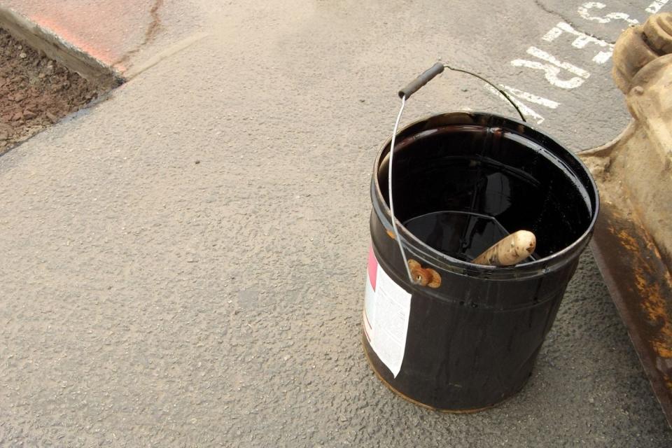 A close up of a tool in a black bucket sitting on a concrete floor. 