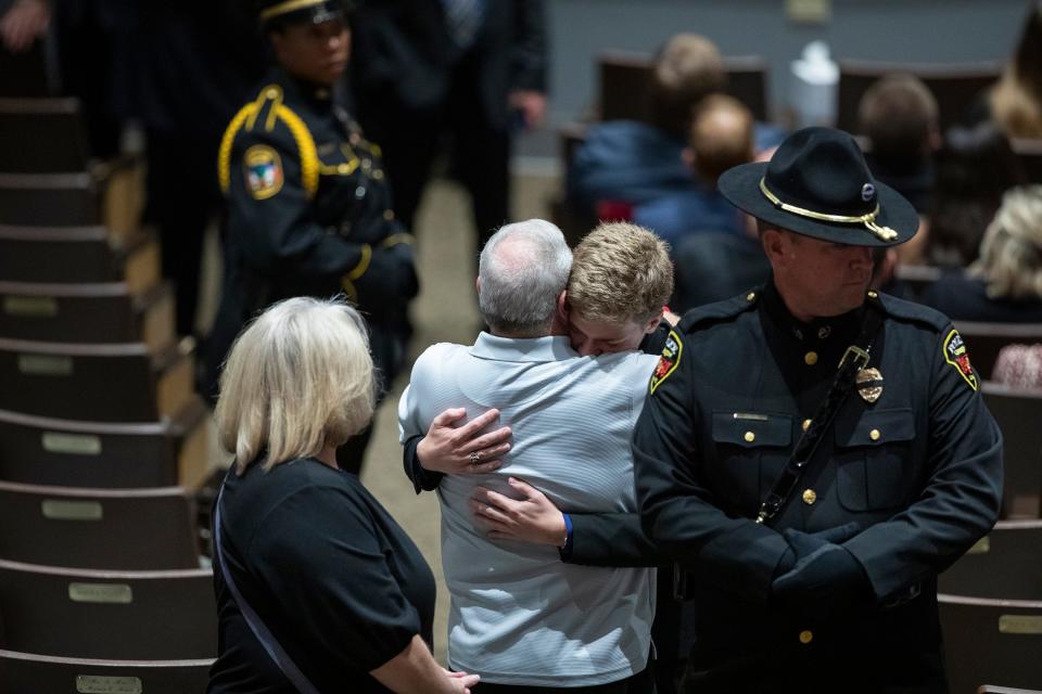 Family members embrace during the funeral for Floyd County Deputy William Petry at the Mountain Arts Center in Prestonsburg, Ky., Tuesday, July 5, 2022.  Petry and two Prestonsburg city police officers were killed while serving a warrant at a home in the county.  (Silas Walker/Lexington Herald-Leader via AP)