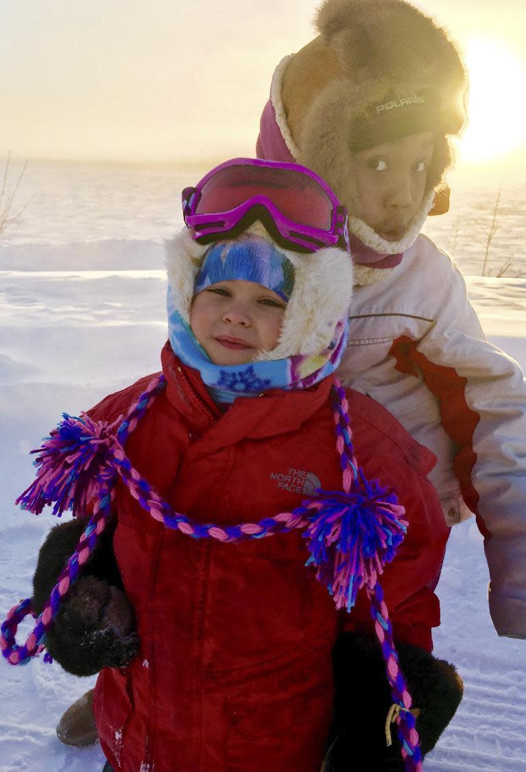 In This Wednesday, Jan. 18, 2017 photo, Carrie and Cuppy Agnes stand for a photo in front of the frozen Yukon River in Tanana, Alaska. The temperature Wednesday at the Tanana airport reached 54 degrees below zero Fahrenheit (-48 Celsius), the coldest recorded in the state, and was 5 degrees colder at -59 F (-51 C) along the river. (Cynthia Erickson via AP)