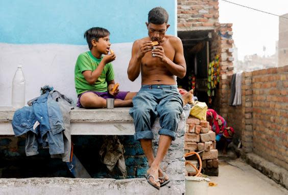 Khan eats breakfast with his son Latif outside their house (Reuters)