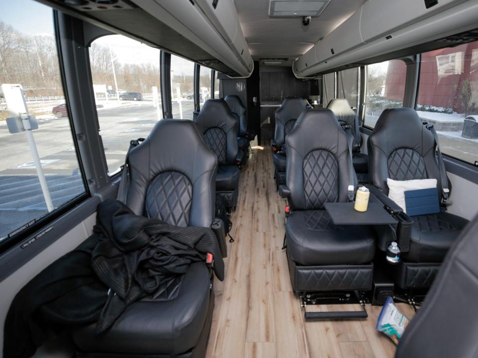 Rows of black leather seats, some topped with jackets, bags, pillows.