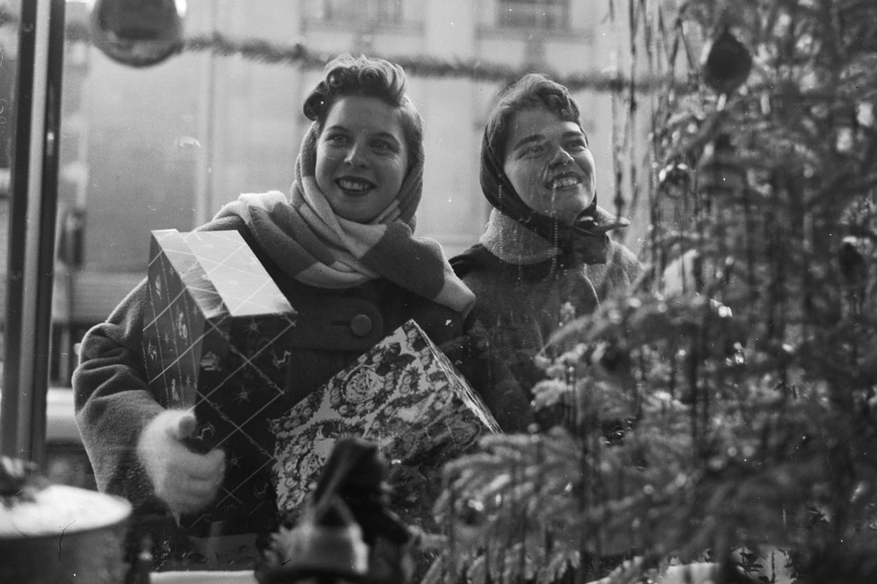 circa 1955: happy christmas shoppers happily gaze at the window displays of the shops of washington dc. 