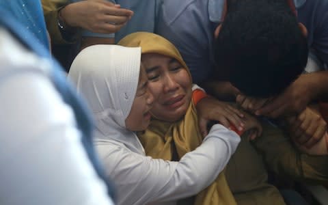 Relatives of passengers comfort each other as they wait for news on a Lion Air plane that crashed off Java Island - Credit: AP