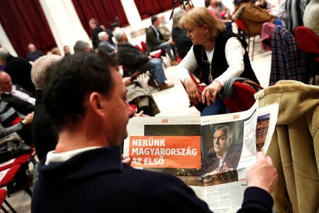 A newspaper shows Hungarian Prime Minister, Viktor Orban as a man reads at a campaign forum of the right-wing Fidesz party in Ercsi, Hungary, March 9, 2018. Picture taken March 9, 2018. REUTERS/Bernadett Szabo