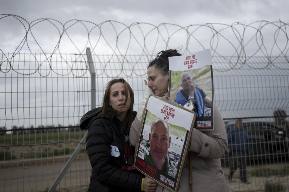 Maya Palty, left, comforts Efrat Machikawa, who both have relatives in Hamas captivity in the Gaza Strip since their kidnapping from Kibbutz Nir Oz on Oct. 7, as families of hostages call out to their loved ones on loudspeakers in hopes that the hostages will hear, at the Gaza border in Kibbutz Nirim, southern Israel, Thursday, Jan. 11, 2024. Maya's relative is Elad Katzir, 47; Efrat's relative is Gadi Moses, 79. (AP Photo/Maya Alleruzzo)