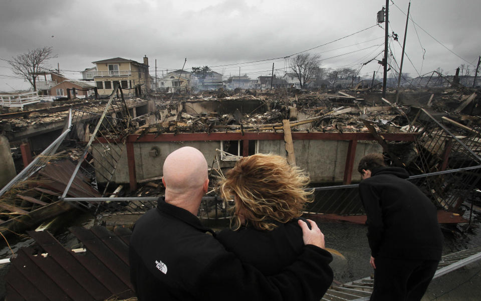 Robert Connolly, left, embraces his wife, Laura, as they survey the remains of the home owned by her parents, in the Breezy Point section of New York, October 2012. (Photo: Mark Lennihan/AP)