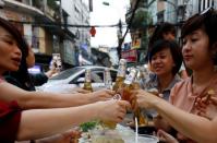 Beer drinkers toast with bottles of tiger beer at a restaurant in the Old Quarter in Hanoi