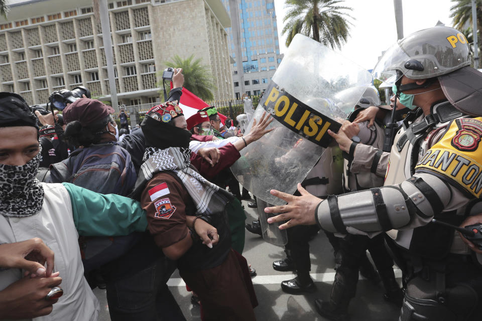 Supporters of Rizieq Shihab, leader of the Islam Defenders Front, scuffle with police officers during a rally in Jakarta, Indonesia, Friday, Dec. 18, 2020. Hundreds of protesters marched in Indonesia's capital on Friday to demand the release of the firebrand cleric who is in police custody on accusation of inciting people to breach pandemic restrictions and ignoring measures to curb the spread of COVID-19 by holding several events, and justice for his six followers who were killed in a shootout with the police. (AP Photo/Tatan Syuflana)