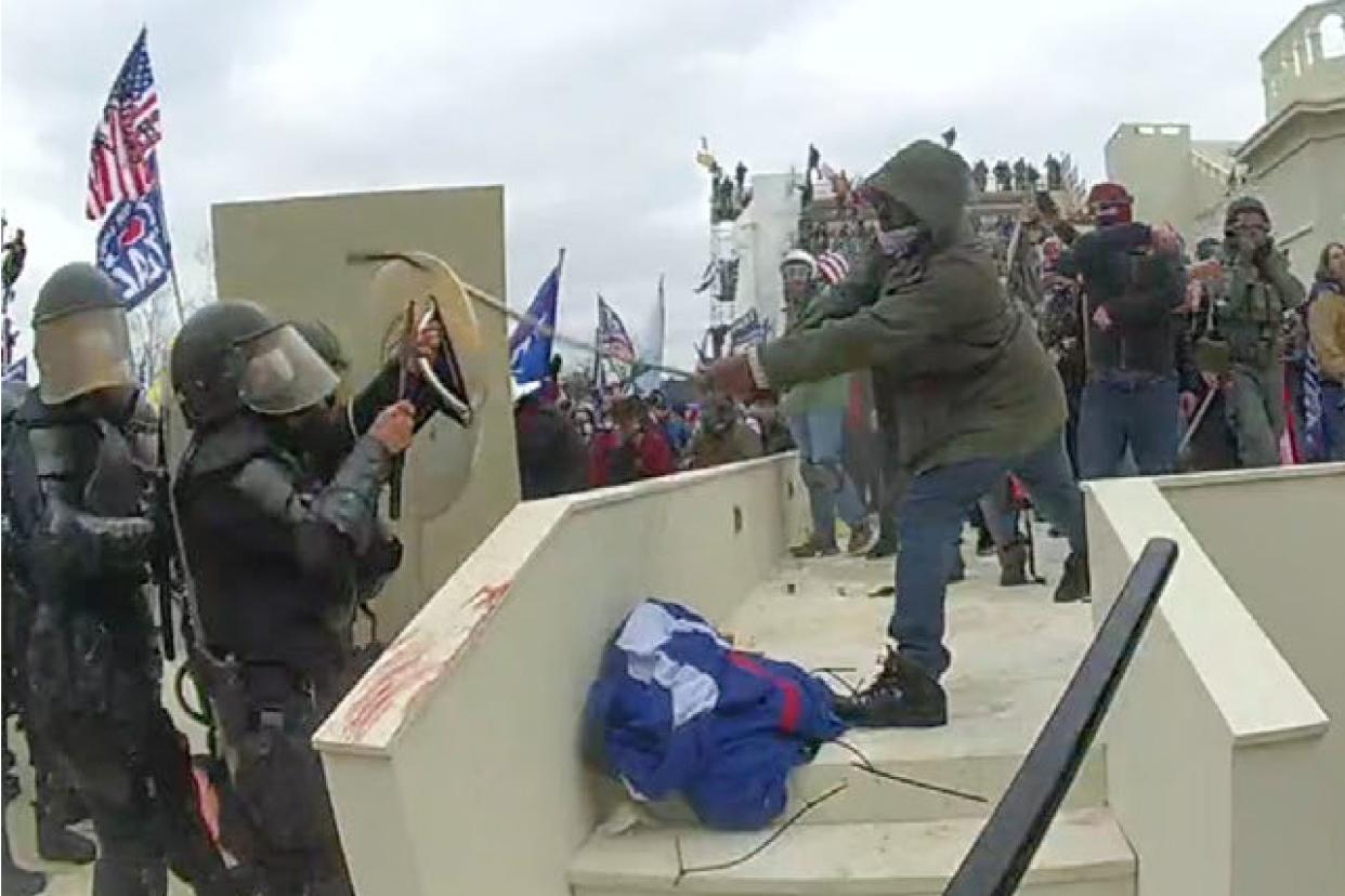 In this image from a Washington Metropolitan Police Department officer's body-worn video camera, and contained in the statement of facts supporting an arrest warrant for Mark Ponder, Ponder strikes an officer with a pole on the West Front of the U.S. Capitol on Jan. 6, 2021. 