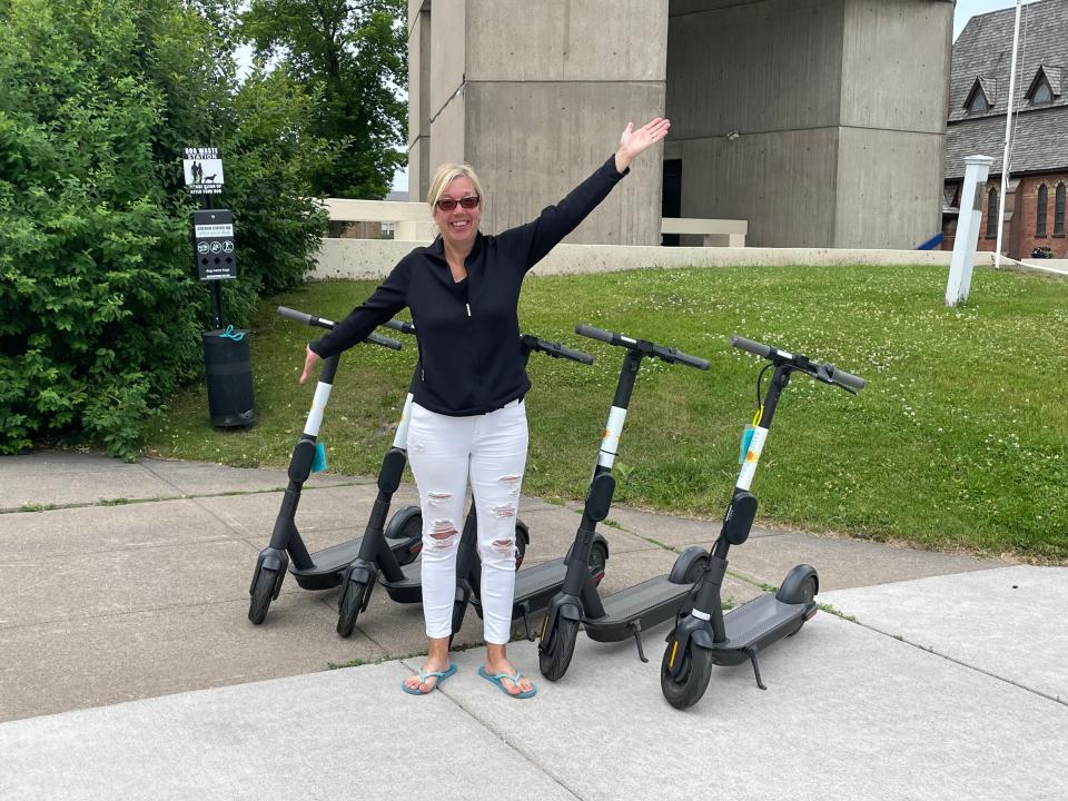 Sherry Garlanger standing in front of some of her e-scooters in front of the Tower of History in Sault Ste. Marie.