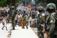 Children walk past Rwandan security forces soldiers in camp for internally displaced in Quitunda