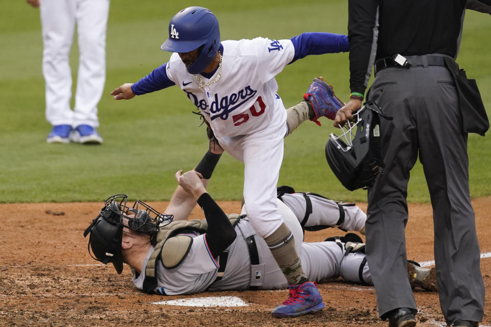 Miami Marlins catcher Chad Wallach, bottom, tags out Los Angeles Dodgers' Mookie Betts (50) at home during the fifth inning of a baseball game Sunday, May 16, 2021, in Los Angeles. Betts ran home after a single hit by Adam Duvall. (AP Photo/Ashley Landis)