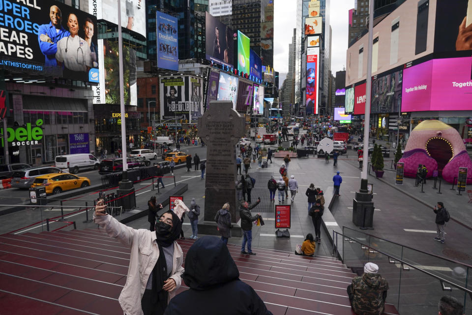 Pedestrians look around Times Square, Monday, Nov. 15, 2021, in New York. Even as visitors again crowd below the jumbo screens in New York’s Times Square, the souvenir shops, restaurants, hotels and entrepreneurs within the iconic U.S. landmark are still reeling from a staggering pandemic. (AP Photo/Seth Wenig)