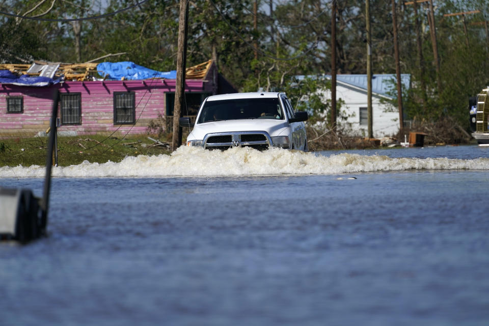 A truck drives through a flooded street in Lake Charles, La., Saturday, Oct. 10, 2020, past a home with damage from Hurricane Laura, after Hurricane Delta moved through on Friday. (AP Photo/Gerald Herbert)