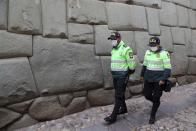 Police walk past the famous wall known as the stone with 12 angles, part of the current Religious Art Museum on Hatun Rumiyoc Street in Cusco Peru, Thursday, Oct. 29, 2020. All major sites around Cusco are currently open for free, in hopes of sparking any tourism after the COVID-19 pandemic brought it to a standstill. (AP Photo/Martin Mejia)
