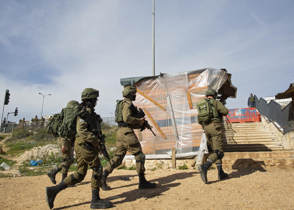 Israeli soldiers secure the area where the military said troops killed a Palestinian man suspected of trying to attack soldiers, at a West Bank junction near the joint Israeli-Palestinian industrial zone of Barkan, Tuesday, Jan. 26, 2021. (AP Photo/Ariel Schalit)