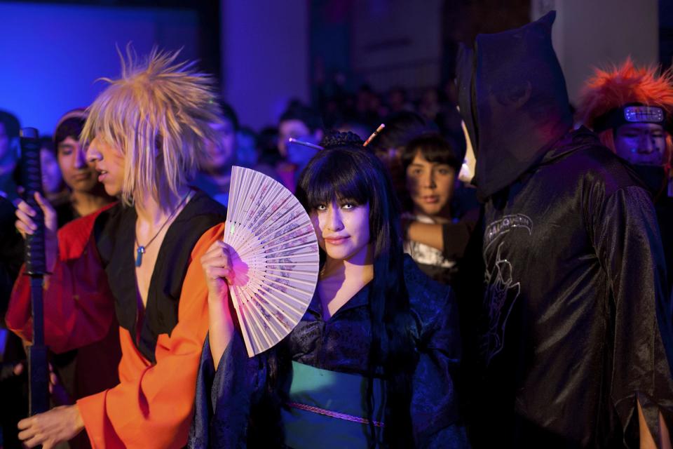 In this May 25, 2013 photo, Silvia, who did not give her last name, holds a fan as she poses for a photo at a party held at a school that was rented for the occasion in Lima, Peru. Silvia and her friends are all dressed in costumes in the style of characters from Korean comic books. Teenagers throughout Latin America have long looked north for pop music inspiration. Now the East is rising, with a large and enthusiastic cult of fans in some countries following the K-pop music from Korea. (AP Photo/Martin Mejia)