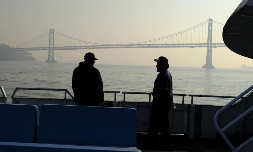 A commuter ferryboat passes by the San Francisco-Oakland Bay Bridge which is obscured by wildfire smoke and haze.