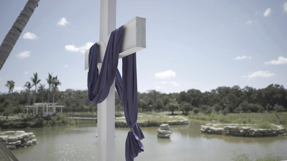 A cross stands near a pond at The Hollow, a 10-acre site in rural Venice, Fla., on July 31, 2022. Michael Flynn has been soliciting money for the venue through a crowdfunding campaign for The America Project, a group he started last year and that AP and Frontline previously reported has been spending millions on efforts to advance its agenda. (Richard Rowley/Frontline via AP)